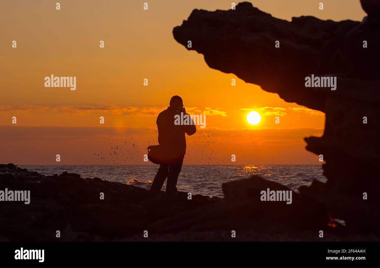 Fotograf fotografiert den Sonnenaufgang auf See. Stockfoto