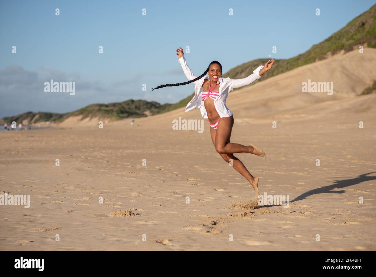 Frau am Strand springt in Aufregung Stockfoto