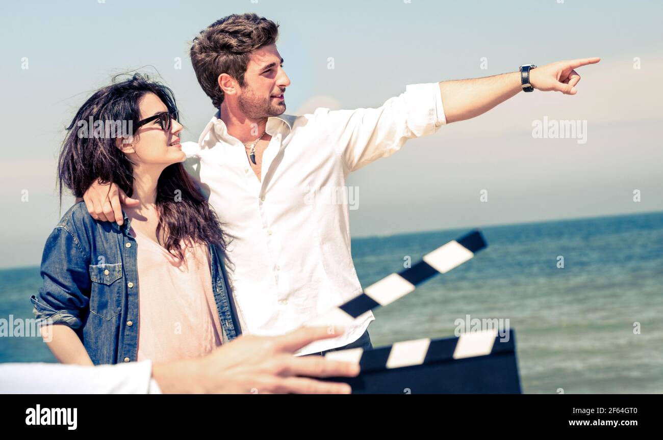 Junges verliebte Paar, das am Strand für einen romantischen Film agiert -  Kinobranche Konzept mit ciak Slate bereit für Film Szene Stockfotografie -  Alamy