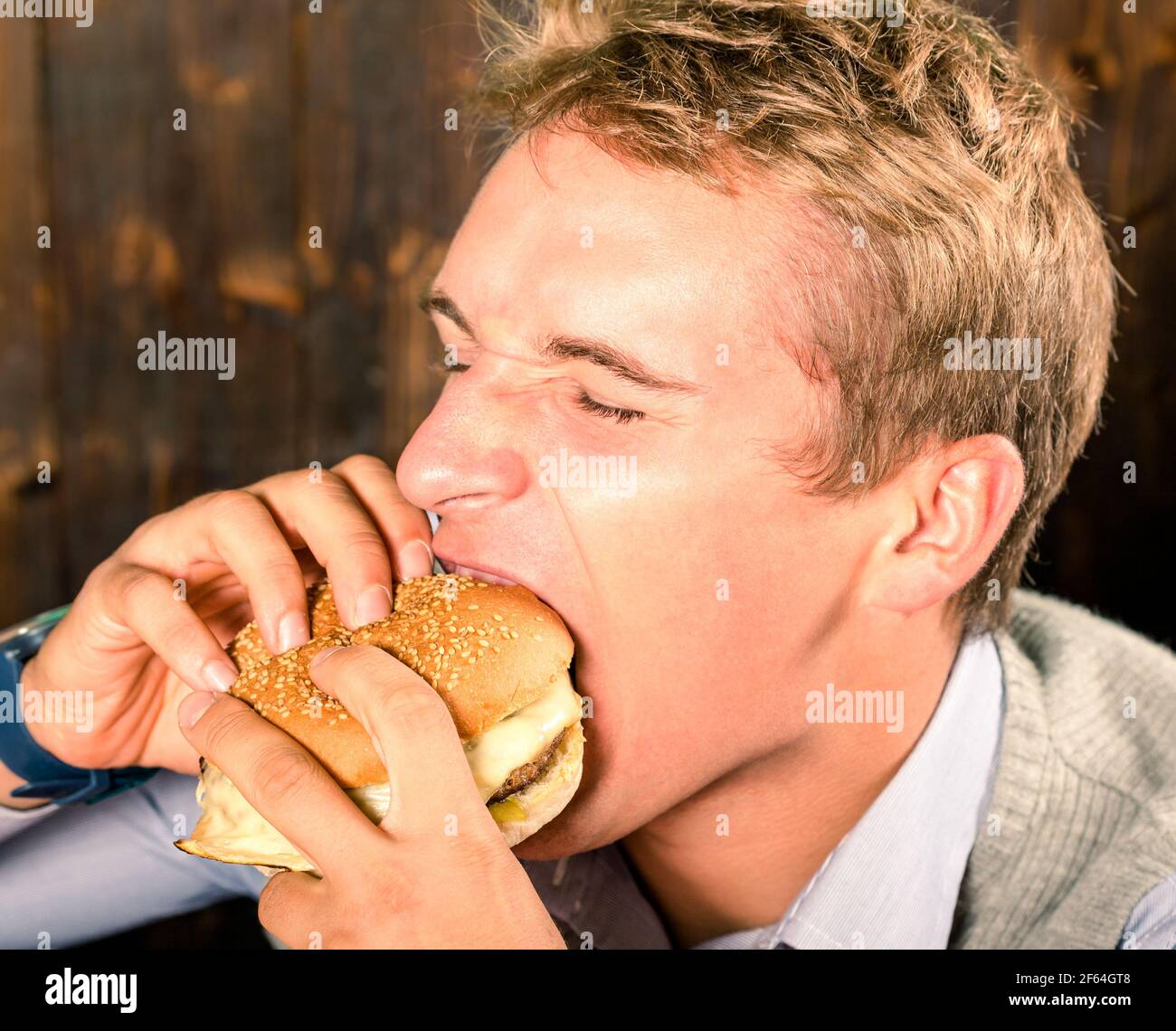 Schöner Mann, der Cheeseburger isst Stockfoto