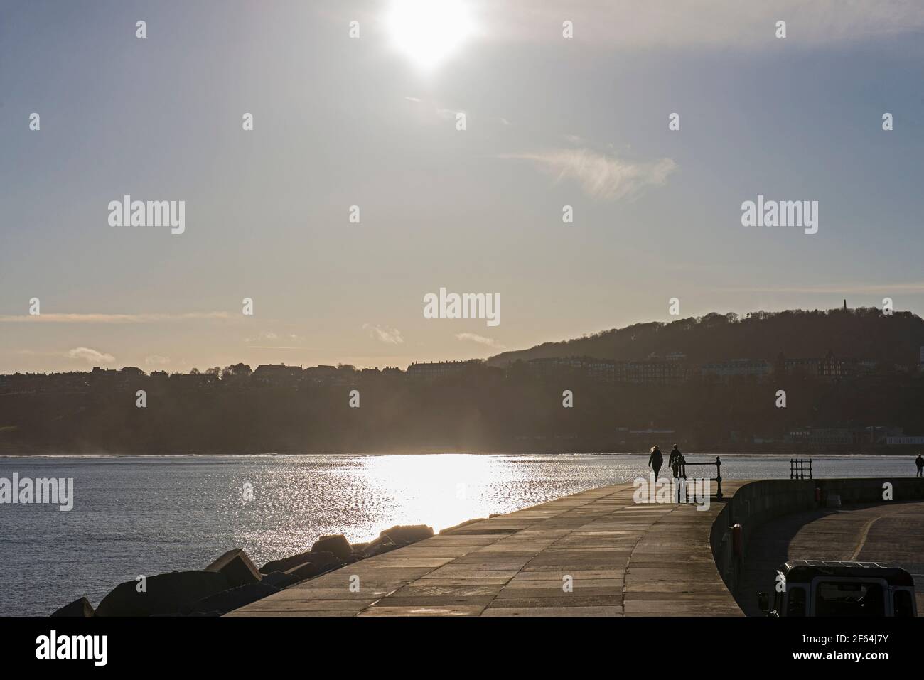 Landschaft Panoramablick auf die Küste Küste Hafen vor Kai mit Paar, die in Silhouette bei Sonnenuntergang spazieren gehen Stockfoto