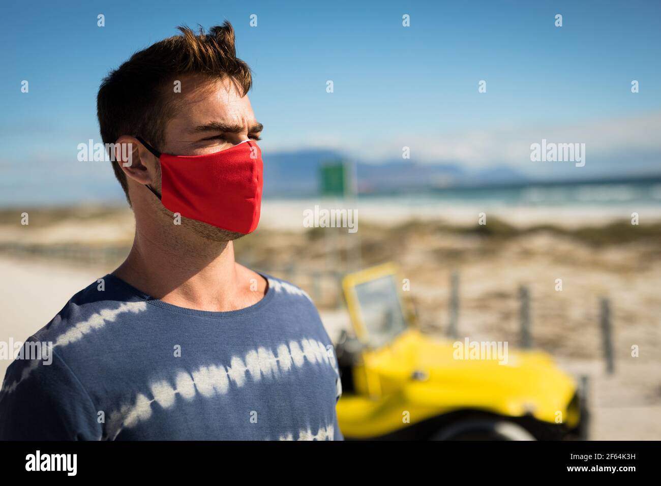 Glücklicher kaukasischer Mann mit Gesichtsmaske neben dem Strandbuggy Blick auf das Meer Stockfoto