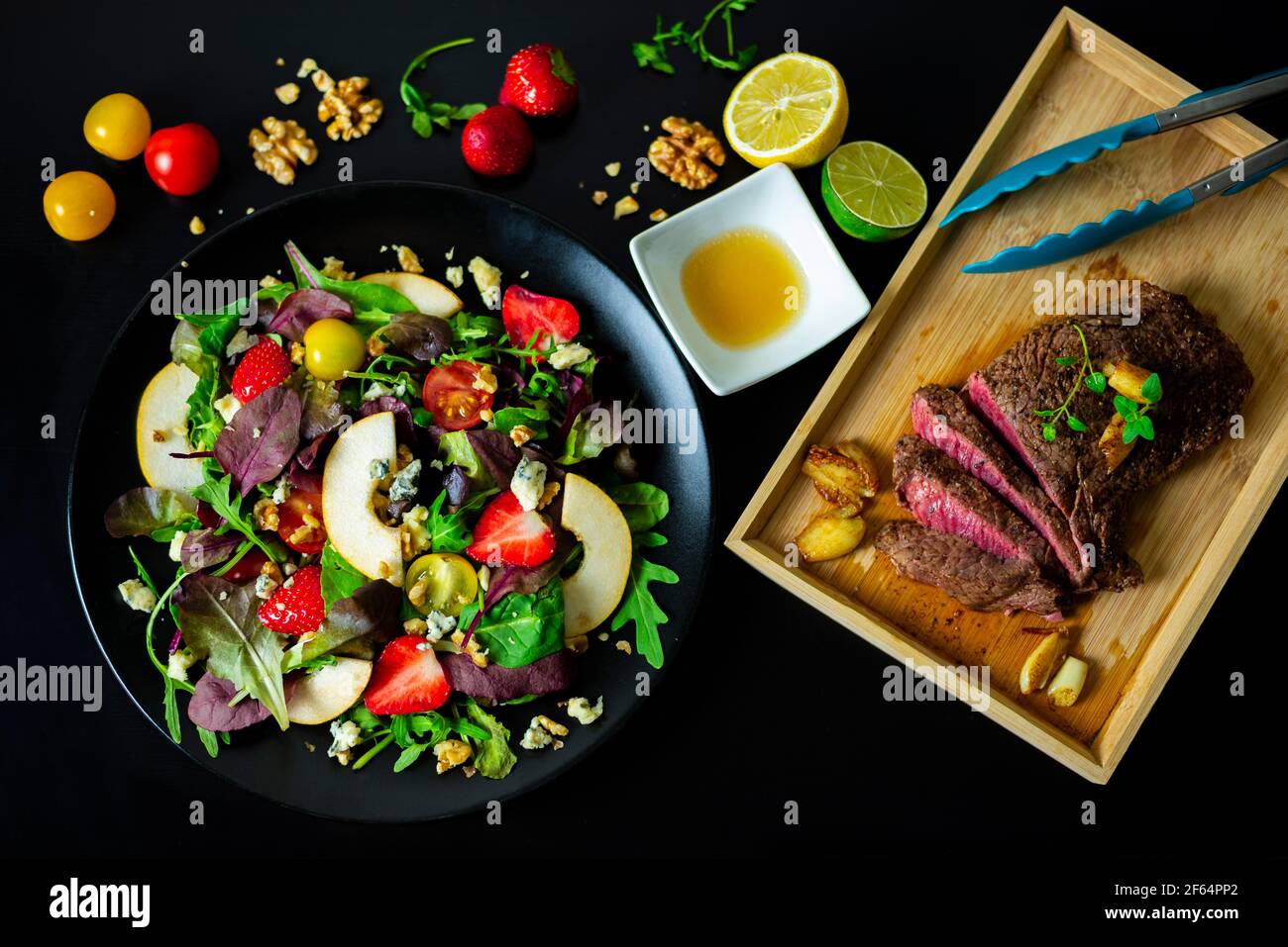 Steak mit gemischtem Salat mit Erdbeeren, Birnen, Walnüssen, Blauschimmelkäse und Zitronen-Honig-Dressing schneiden Stockfoto