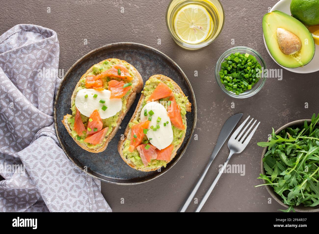 Leckeres herzhaftes Frühstück, Sandwiches mit Avocado-Paste, Lachs und Mozzarella auf einem Teller, Rucola und Erbsensprossen und grüne Zwiebel Stockfoto