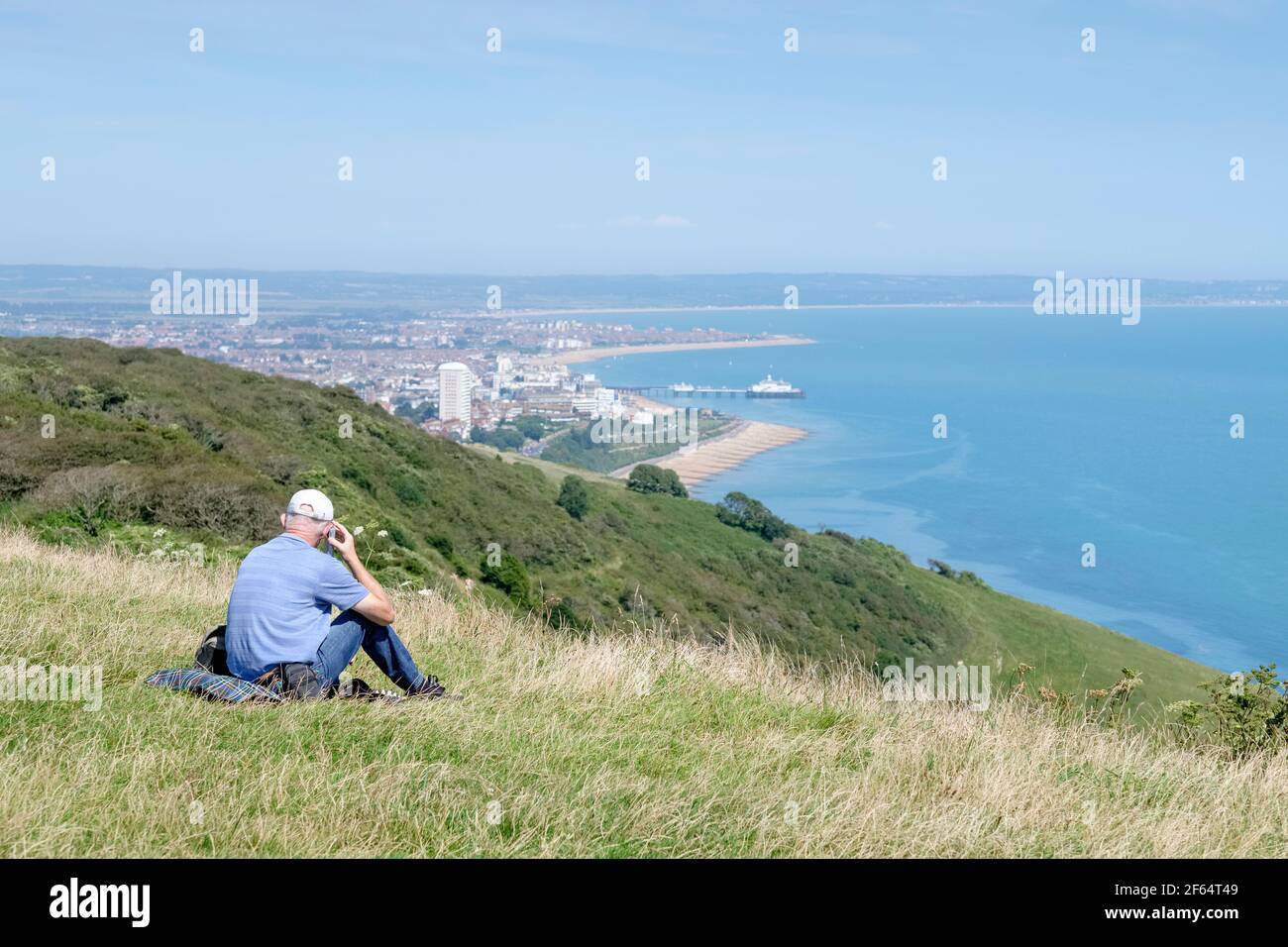Älterer Mann, der auf den Kreidefelsen über Eastbourne, East Sussex, Großbritannien, Radio hört Stockfoto