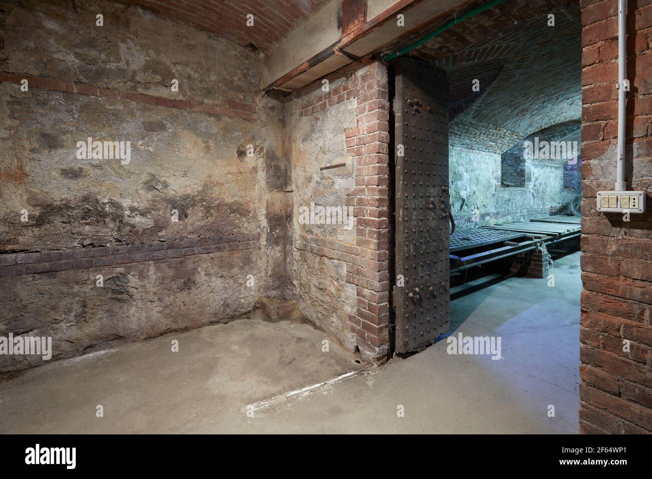 Altes, leeres Untergeschoss mit Ziegelwänden und Holzportal Stockfoto