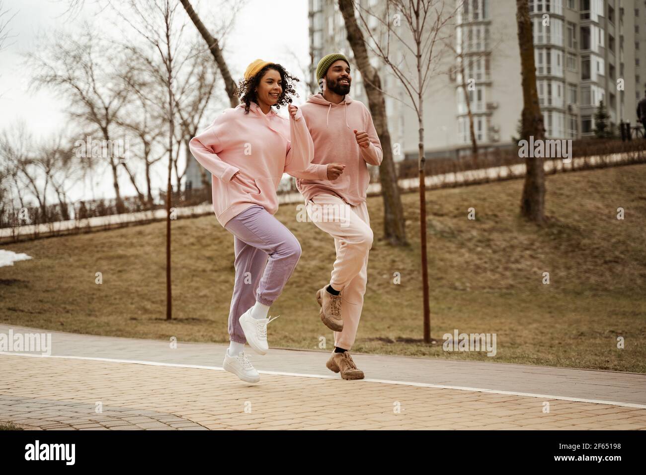 Junge afroamerikanische Athleten in Sportbekleidung laufen auf Platz im Freien Stockfoto