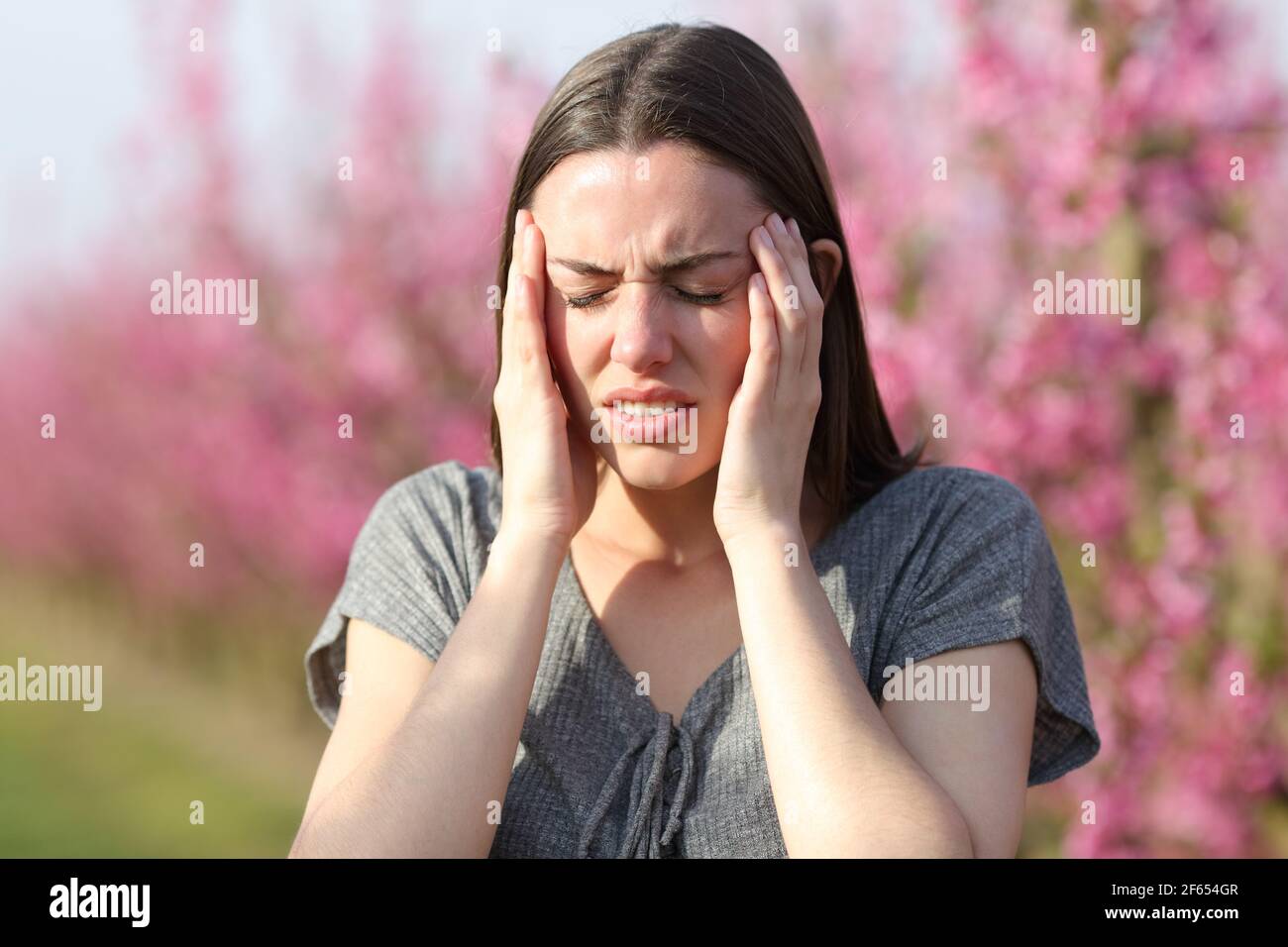 Frau leidet Migräne in einem blühenden Feld in einem sonnigen Tag Stockfoto