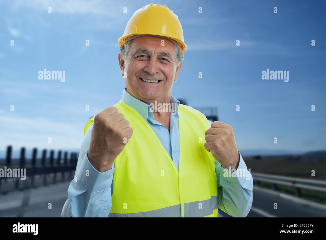 Happy adult männlich alten Konstruktor trägt gelben Hardhat und fluoreszierend Weste machen feiert Erfolg Geste mit Fäusten fröhlichen Ausdruck Stockfoto