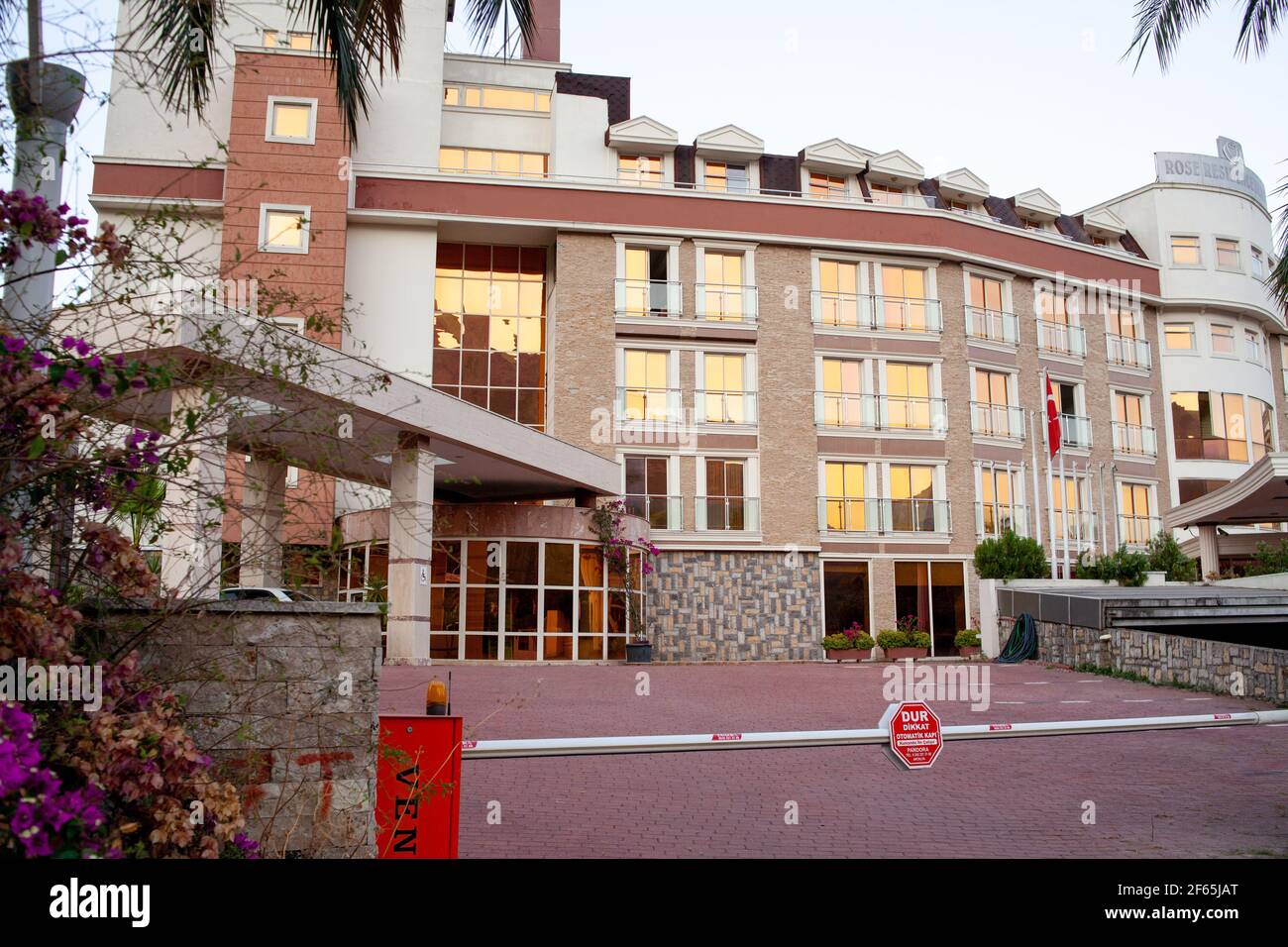 Kemer, Türkei - 02,07.2020. Geschlossenes Hotelgebäude wegen Coronavirus auf Atatürk blvd mit goldfarbenen Fenstern im Sonnenuntergang. Stockfoto