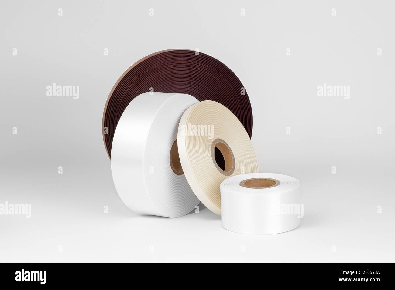 Set von vier Rollen Satinbänder in weiß, beige, braun für Etikett oder Dekoration, isoliert auf einem weißen, grauen Hintergrund Stockfoto