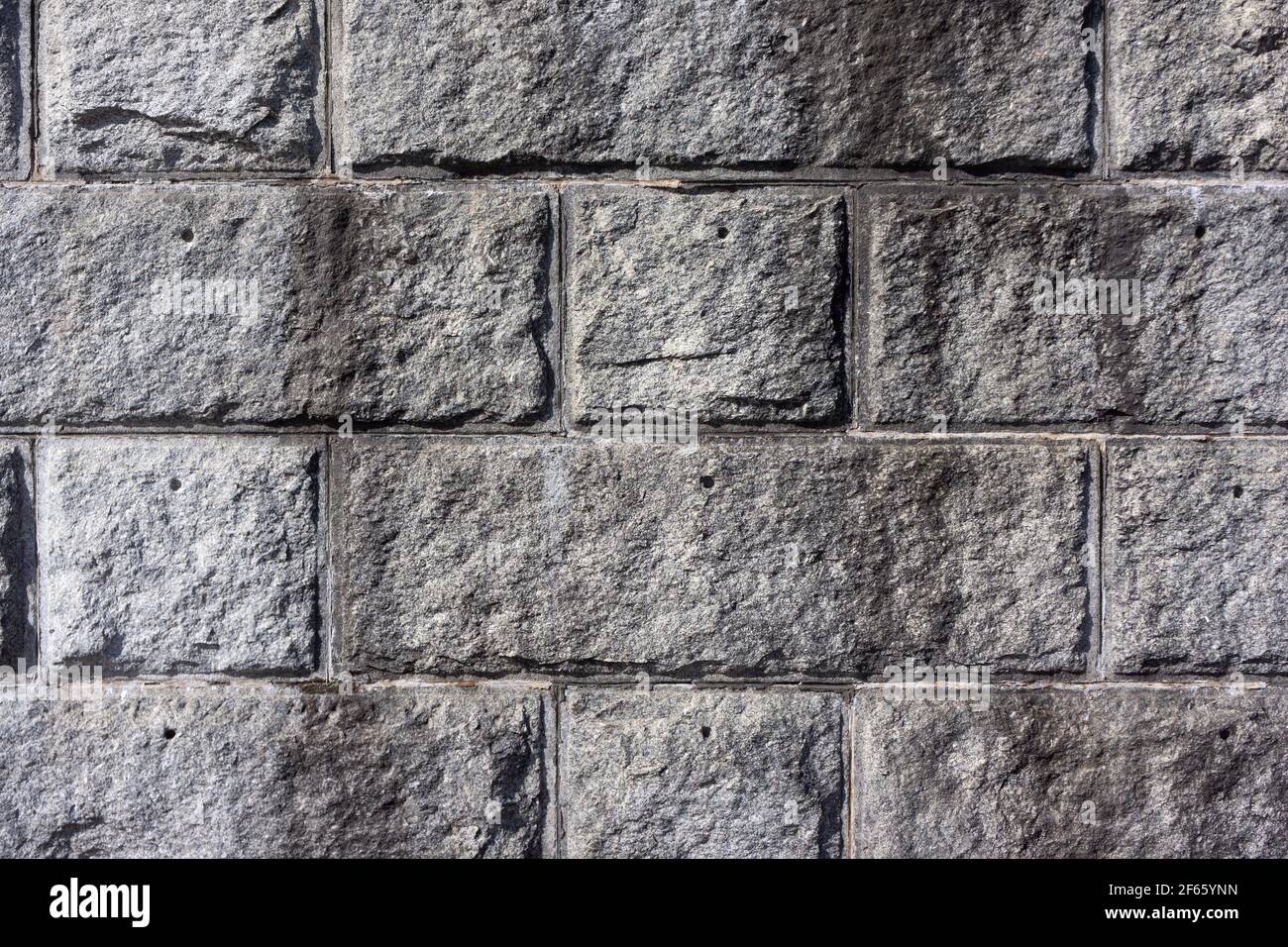 Große behauene Granitsteine einer Verteidigungsmauer mit Fugen zwischen dem Stein im frühen Morgenlicht. Stockfoto