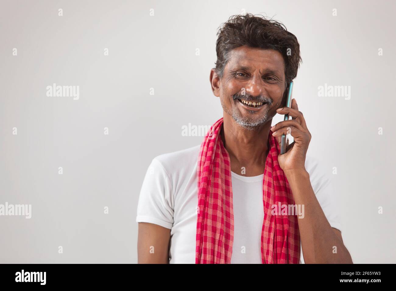 PORTRÄT EINES LANDMANNS, DER ÜBER MOBILTELEFON UND SPRICHT LÄCHELND Stockfoto