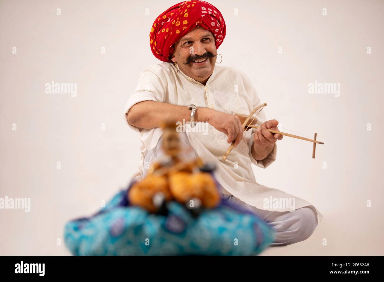 EIN GLÜCKLICHER LÄNDLICHER KÜNSTLER, DER FÜR DIE KATHPUTLI-SHOW EIN INSTRUMENT SPIELT Stockfoto