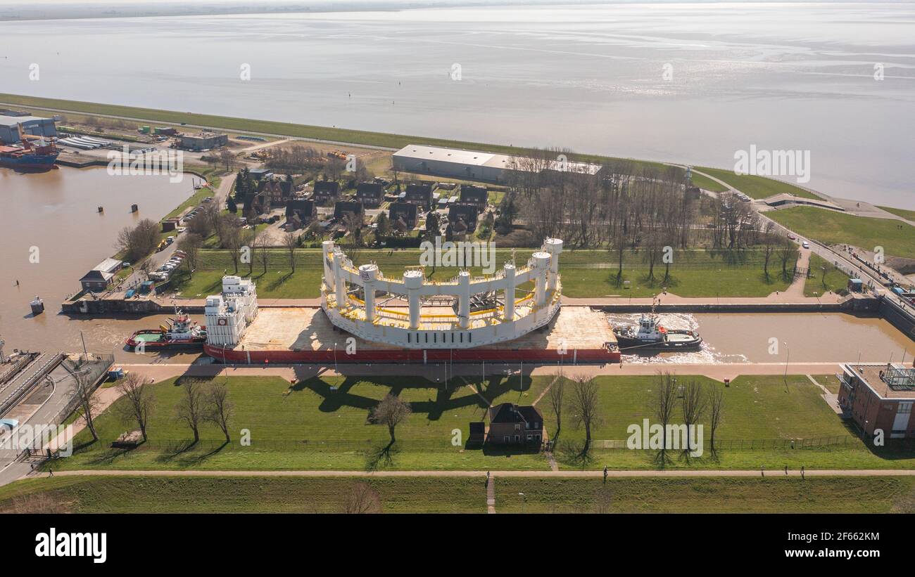 Emden, Deutschland. März 2021, 30th. Die 1600 Tonnen schwere Komponente für eine Tiefsee-Lachsfarm, gebaut von der Emder Werft 'Fosen Yard', wird auf einem Ponton von zwei Schleppern vom Emder Hafen durch die große Seeschleuse bewegt und soll nach Norwegen transportiert werden. Kredit: Mohssen Assanimoghaddam/dpa/Alamy Live Nachrichten Stockfoto