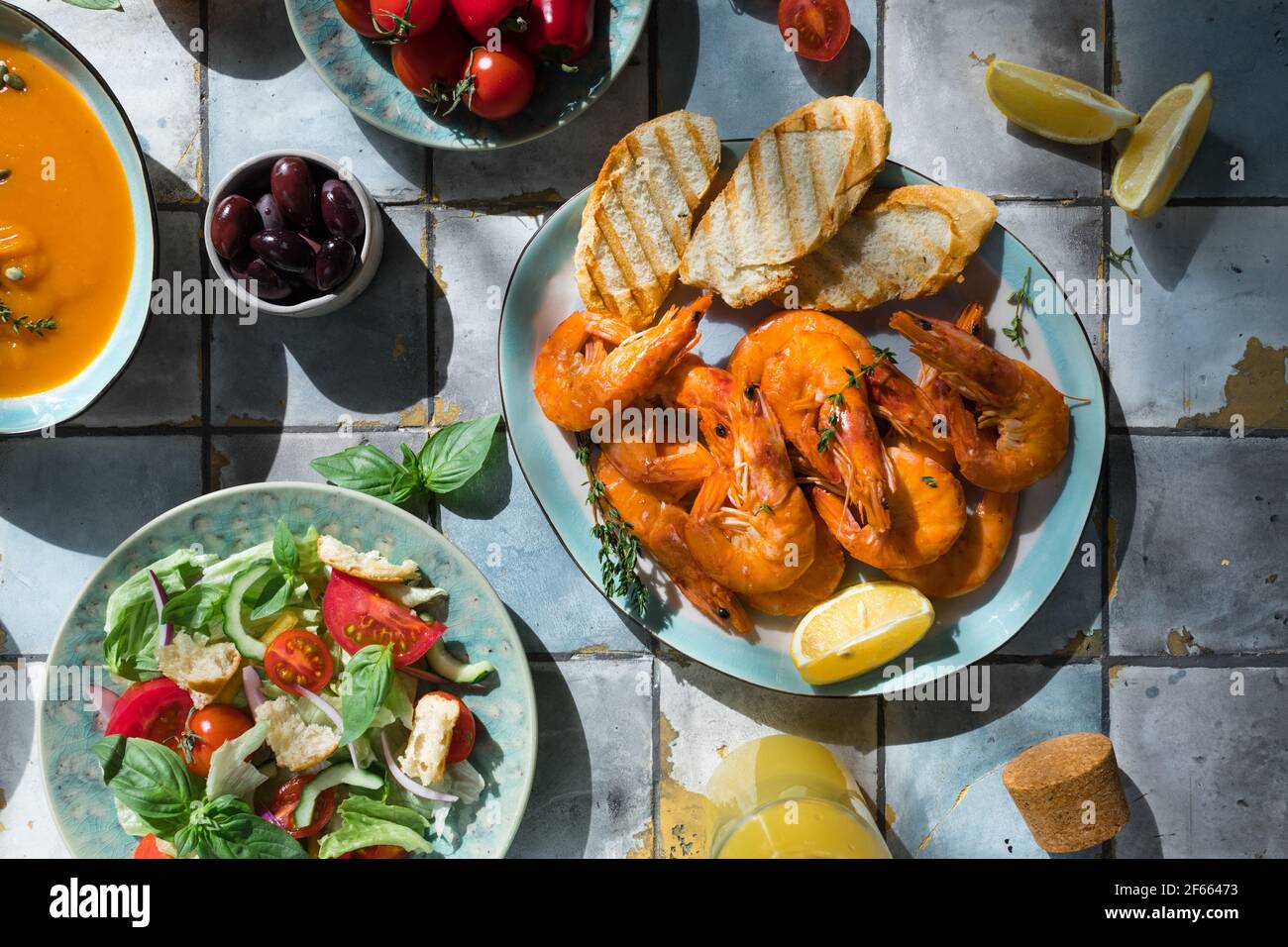 Mediterrane Gerichte am Kacheltisch: Meeresfrüchte-Garnelen, Gemüsesalat, Kürbissuppe, Samen Stockfoto