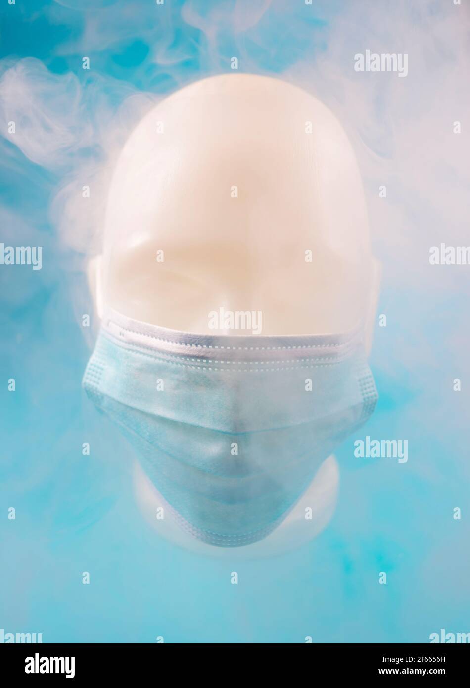 Minimalistische abstrakte Komposition Hintergrund eines menschlichen Gesichts trägt eine Maske, mit Rauch bedeckt, auf einem blauen Hintergrund. Stockfoto