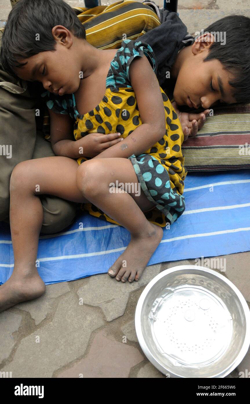 Straße Kinder schlafen auf einer belebten Straße Kalkutta uneingedenk der Menge um Sie. Bevölkerung der Gehsteig wohnen in Kolkata ist etwa einen halben Stockfoto