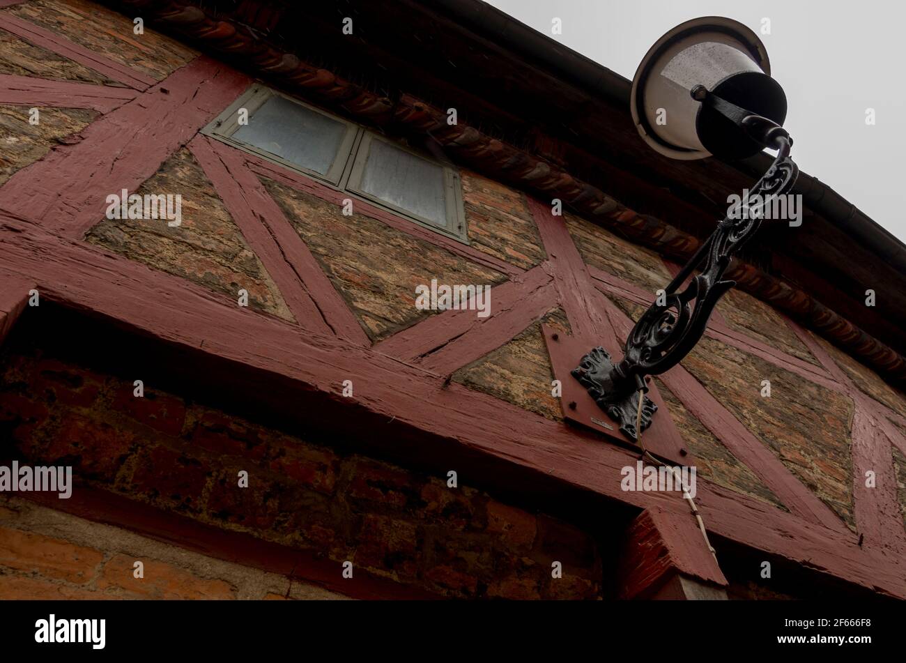 Ein altes Haus in Stortorget, Ystad, Schweden, das aus Ziegelsteinen und einem roten Holzrahmen gebaut wurde. Eine Lampe ragt aus dem Türrahmen. Stockfoto