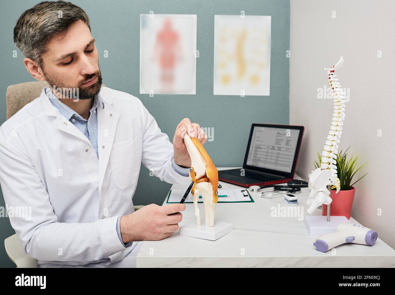 Reifer Arzt mit einem Knie-Gelenk anatomischen Modell zur Analyse der menschlichen Knieprobleme Bereiche und Behandlung Stockfoto