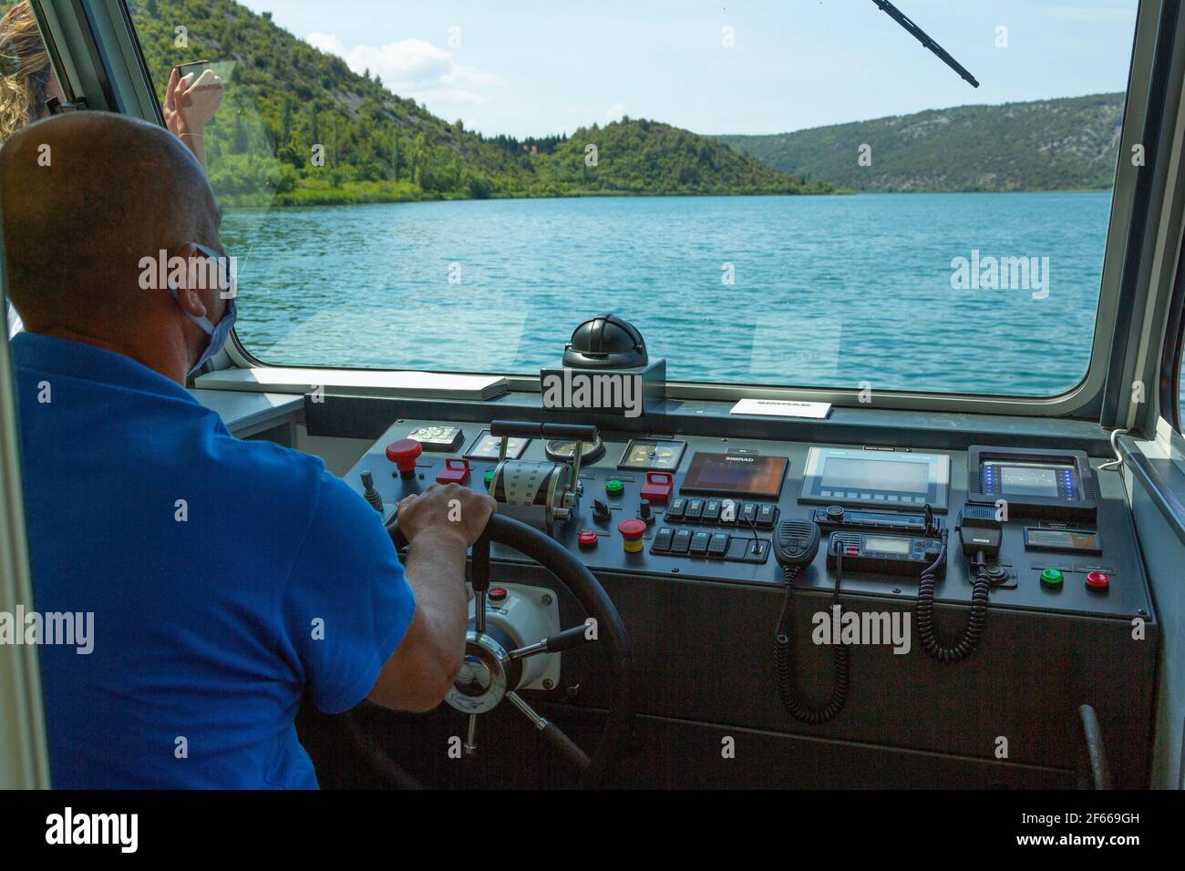 SKIPPER MIT MASKE FÄHRT ELEKTROBOOT AUF DEM FLUSS KRKA Stockfoto