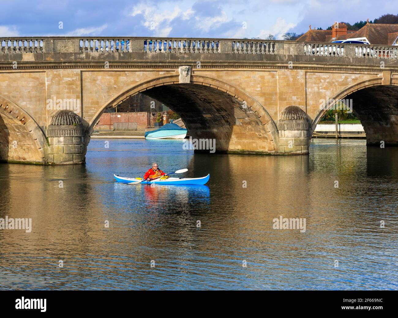 Kanute, die in Henley-on-Thames, Oxfordshire, England, durch die alte Henley Bridge, die über die Themse führt, gepaddelt war Stockfoto