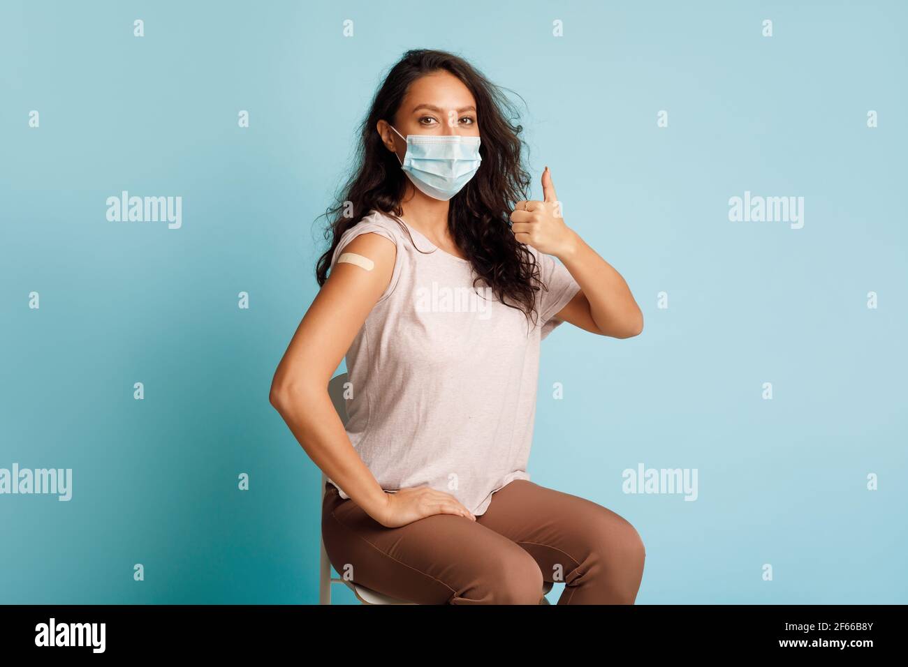 Geimpfte Frau Gestikuliert Thumbs-Up Nach Coronavirus-Impfung Auf Blauem Hintergrund Stockfoto