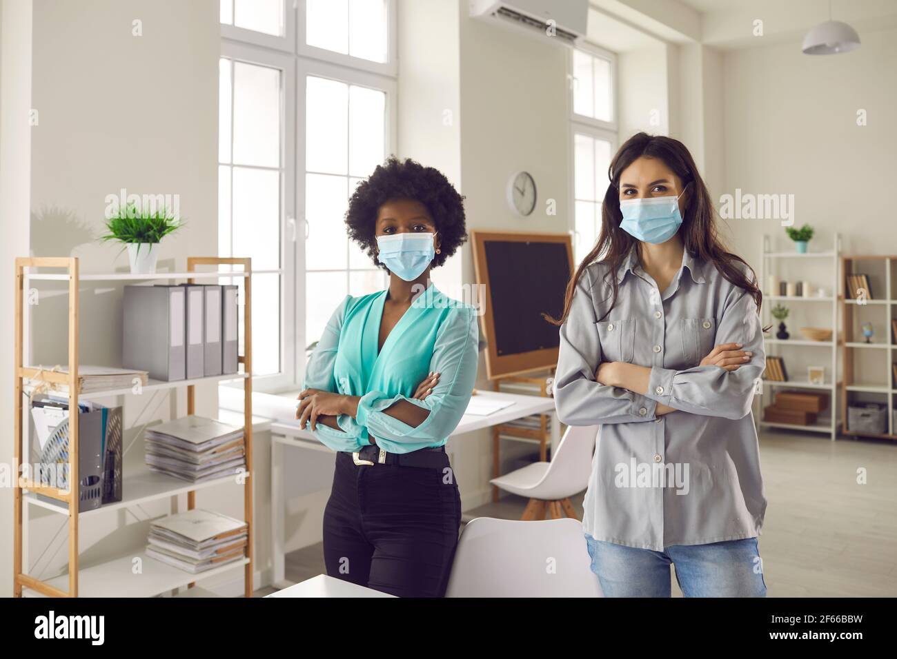 Portrait von interracial Geschäftsfrau tragen Maske im Büro Blick auf Kamera Stockfoto
