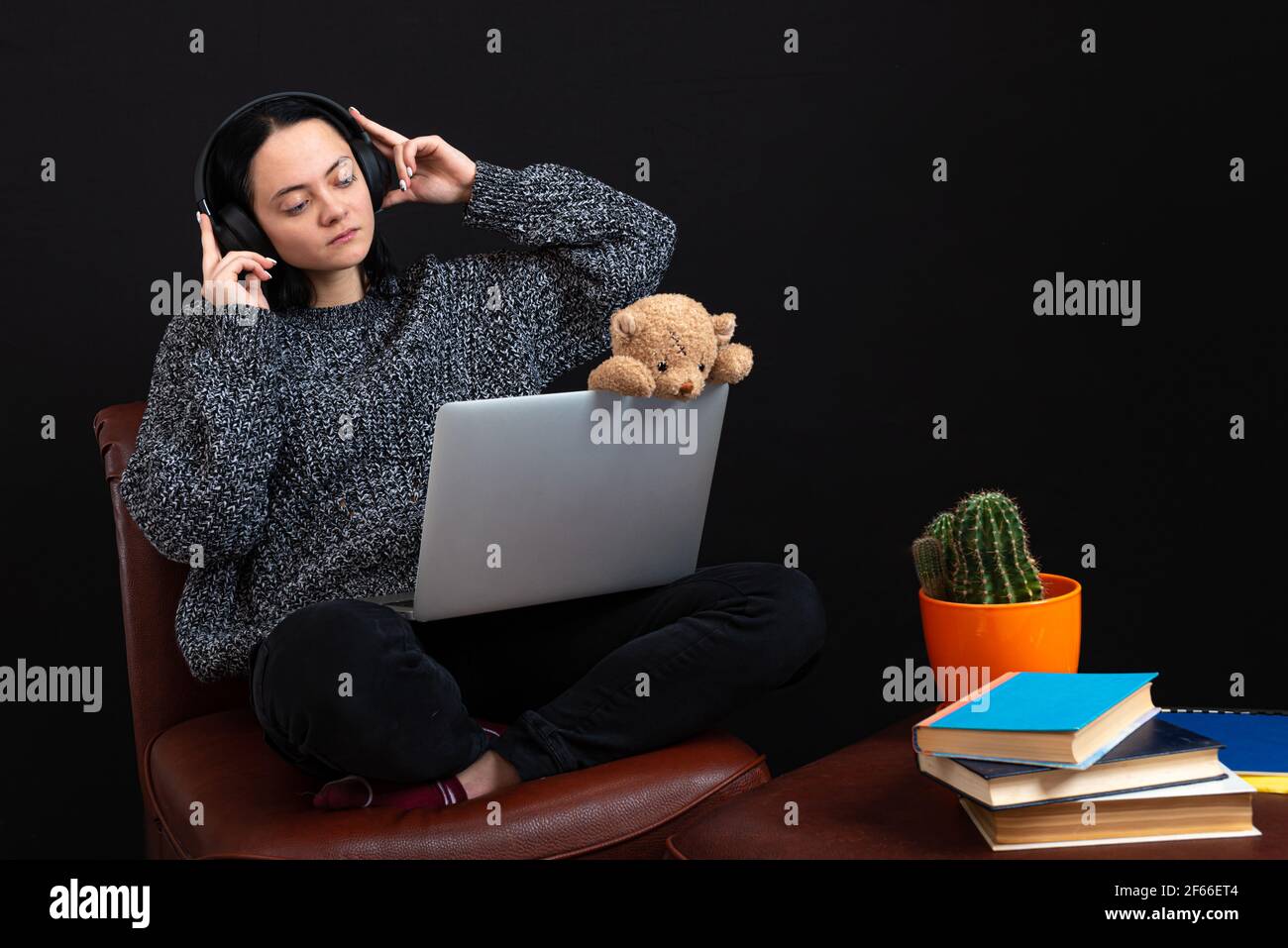 Teenager Mädchen mit Laptop, Kopfhörer und Teddybär sitzen, Ilistening Musik und Surfen im Internet Stockfoto