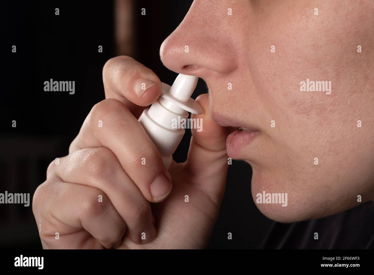 Kranke Frau puffs Nasenspray in ihre Nase Nahaufnahme. Stockfoto