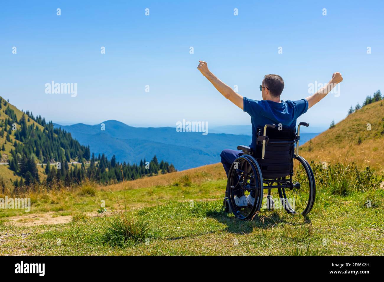 Junger Mann im Rollstuhl an der frischen Luft an einem sonnigen Tag auf dem Berg Stockfoto