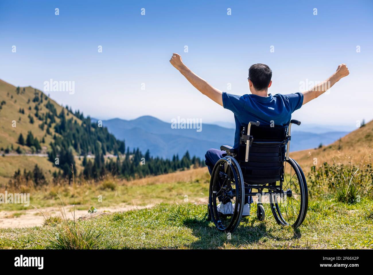 Junger Mann im Rollstuhl an der frischen Luft an einem sonnigen Tag auf dem Berg Stockfoto