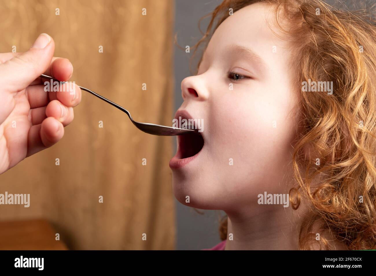 Kleines Mädchen 4 Jahre alt trinkt Hustensaft von einem Löffel, das Kind nimmt Medikamente aus der Nähe Stockfoto