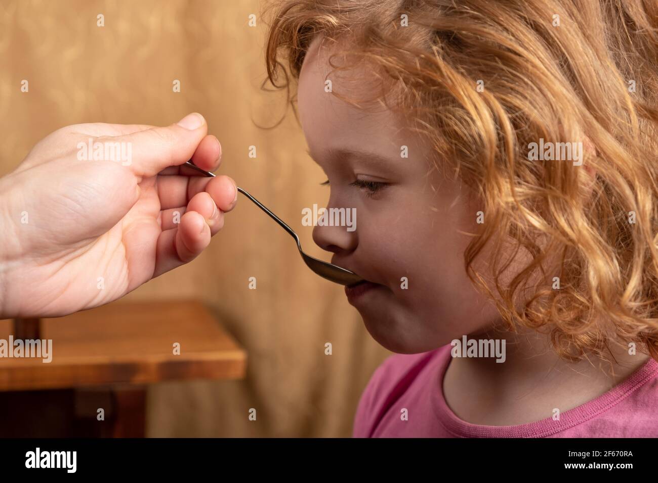 Kleines Mädchen 4 Jahre alt trinkt Hustensaft von einem Löffel, das Kind nimmt Medikamente Stockfoto