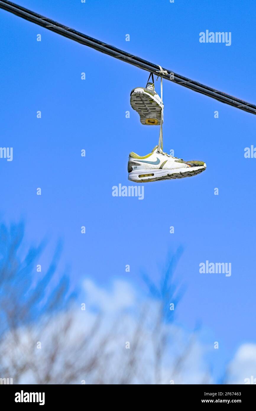 Weggeworfene Nike Laufschuhe über Versorgungskabel geschleudert Stockfoto