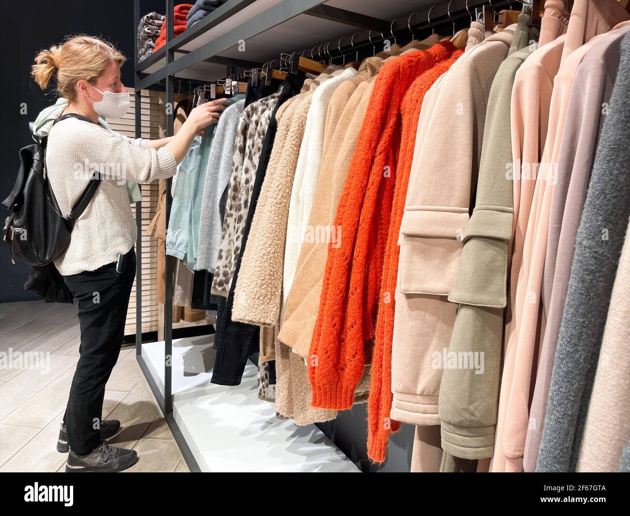 Frau mit Schutzmaske Einkaufen in einem Bekleidungsgeschäft. Stockfoto