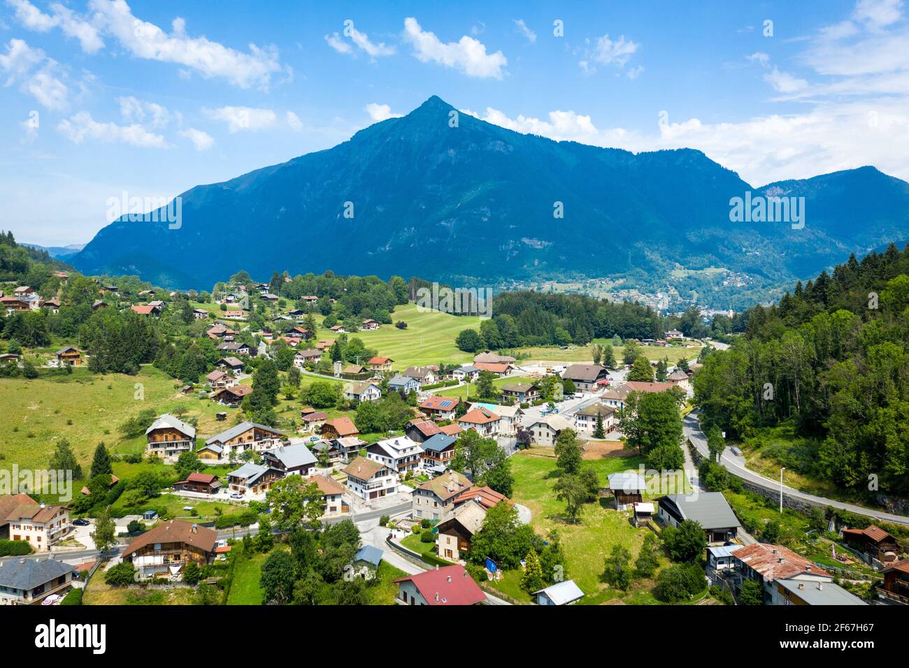 Drohnenansicht von Häusern im alpinen Bergdorf. Markante scharfe Spitze auf Bergrücken im Hintergrund. Schönheit der Giffre-Bergregion, Frankreich. Stockfoto