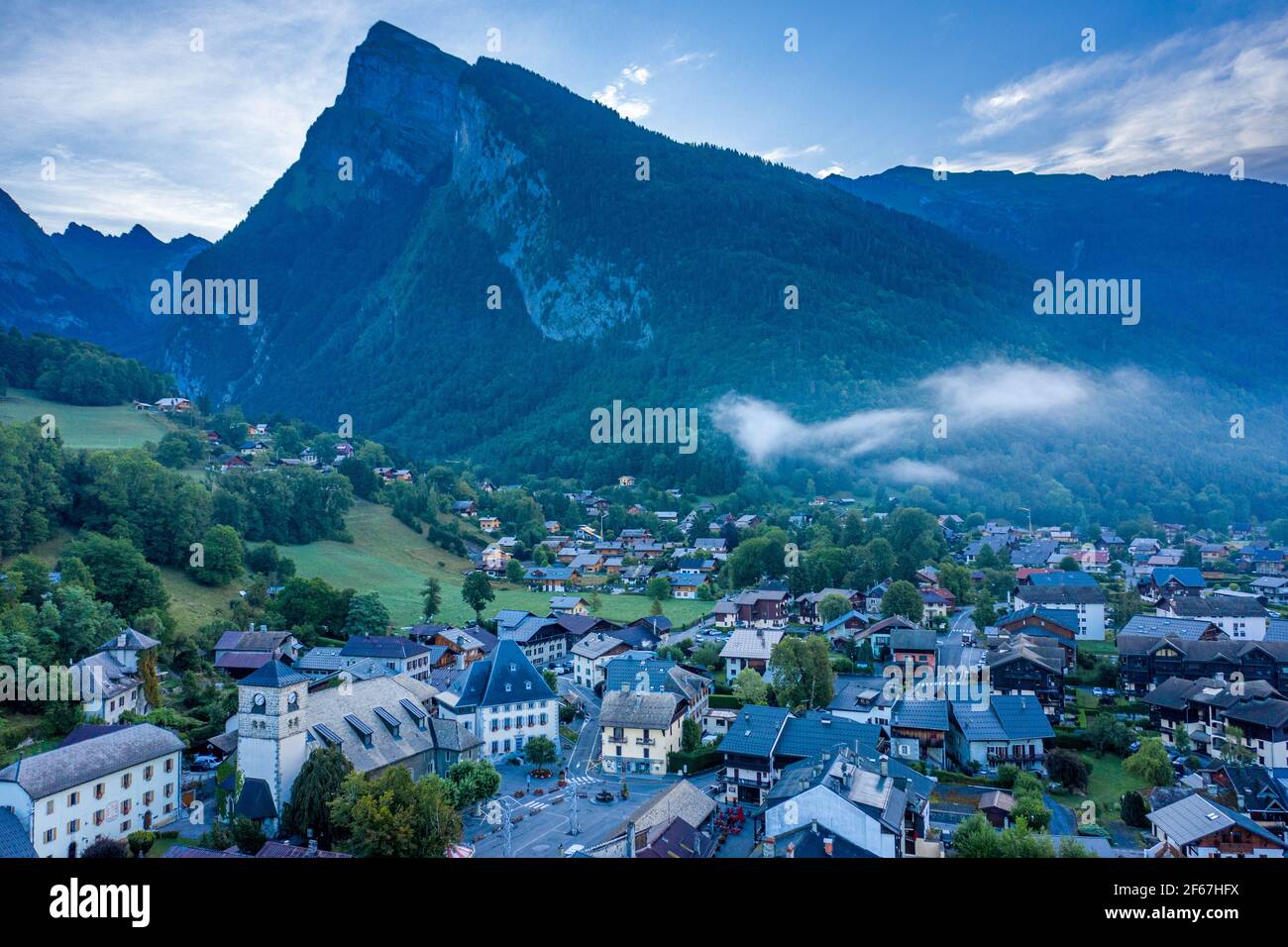Drohnenansicht der kleinen Stadt im Tal unter steilem und scharfem Berggipfel. Schönheit der Giffre-Bergregion, Frankreich. Stockfoto