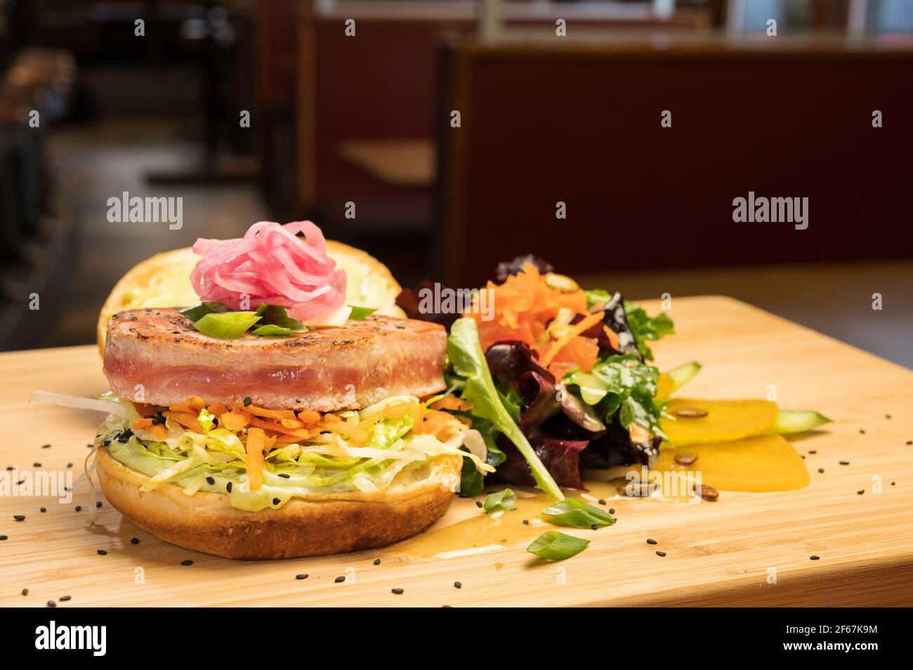 Asiatisches Thunfisch-Sandwich bei einem Abendessen. Gegrillter Gelbflossen-Thunfisch, Zitrusschlaw, asiatischer Tsatziki und eingelegte Zwiebel. Stockfoto