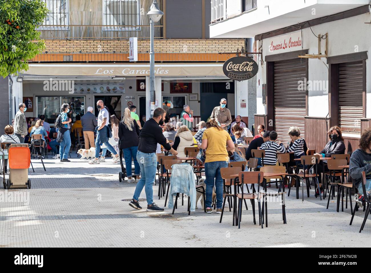 Punta Umbria, Huelva, Spanien - 21. März 2021: Die Leute, die auf der Terrasse eines Cafés und einer Bar in der Straße calle Ancha von Punta Umbria sitzen, tragen Protecti Stockfoto