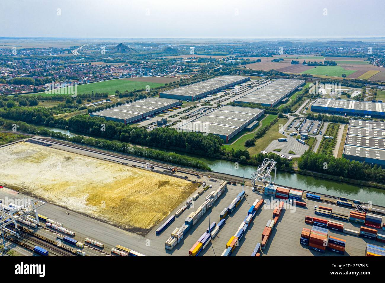 Schiffscontainer in intermodaler Umschlagwerft an der Wasserkanalbank. Großes logistisches Areal im Hintergrund. Transport und Logistik. Stockfoto