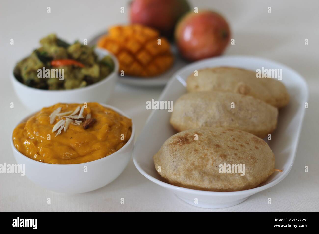 Puri serviert mit Mangopellstoff und Kartoffelmasala. Lokal bekannt als puri Masala und Aamras. Beliebte nordindische Küche im Sommer. Stockfoto