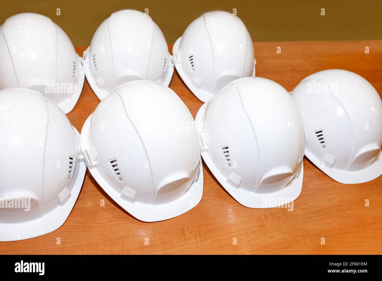 Konstruktion weiße Helme stehen in einer Reihe auf dem Tisch. Das Konzept der Arbeitssicherheit. Stockfoto