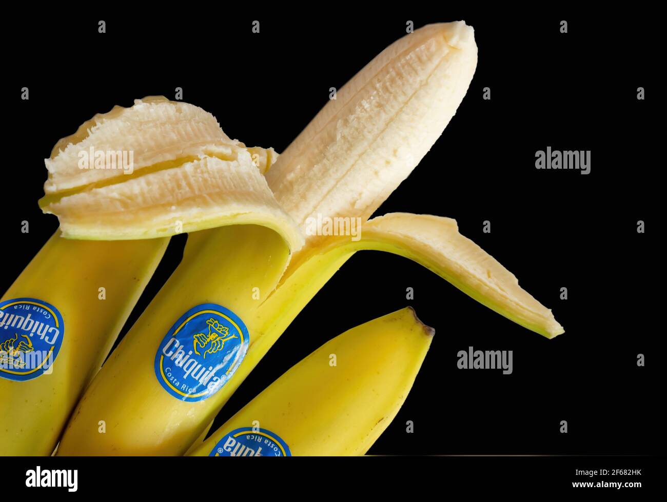 Reife Bananen mit Label isoliert auf schwarzem Hintergrund Stockfoto