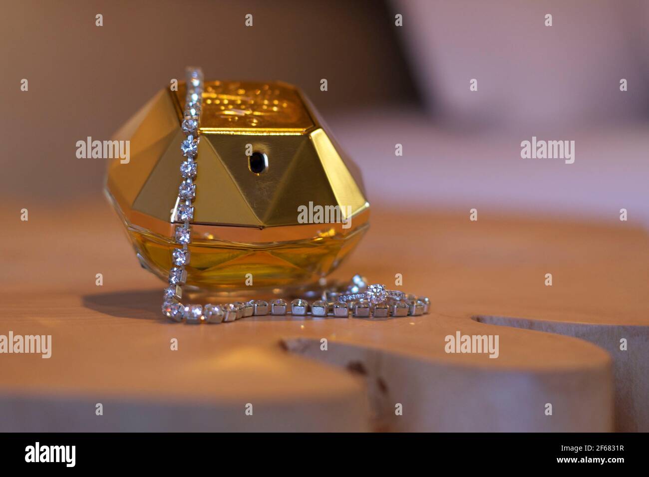 Parfümflasche aus Gold der Braut mit Diamantarmband auf Holztisch. Stockfoto