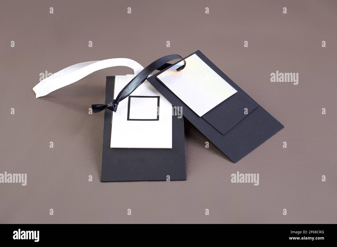 Makro-Mock-up leeres schwarz-weißes Papier-Tag mit Schwarz-weißes Satinband für Markenlogo auf Grün Baumwollmaterial Stockfoto