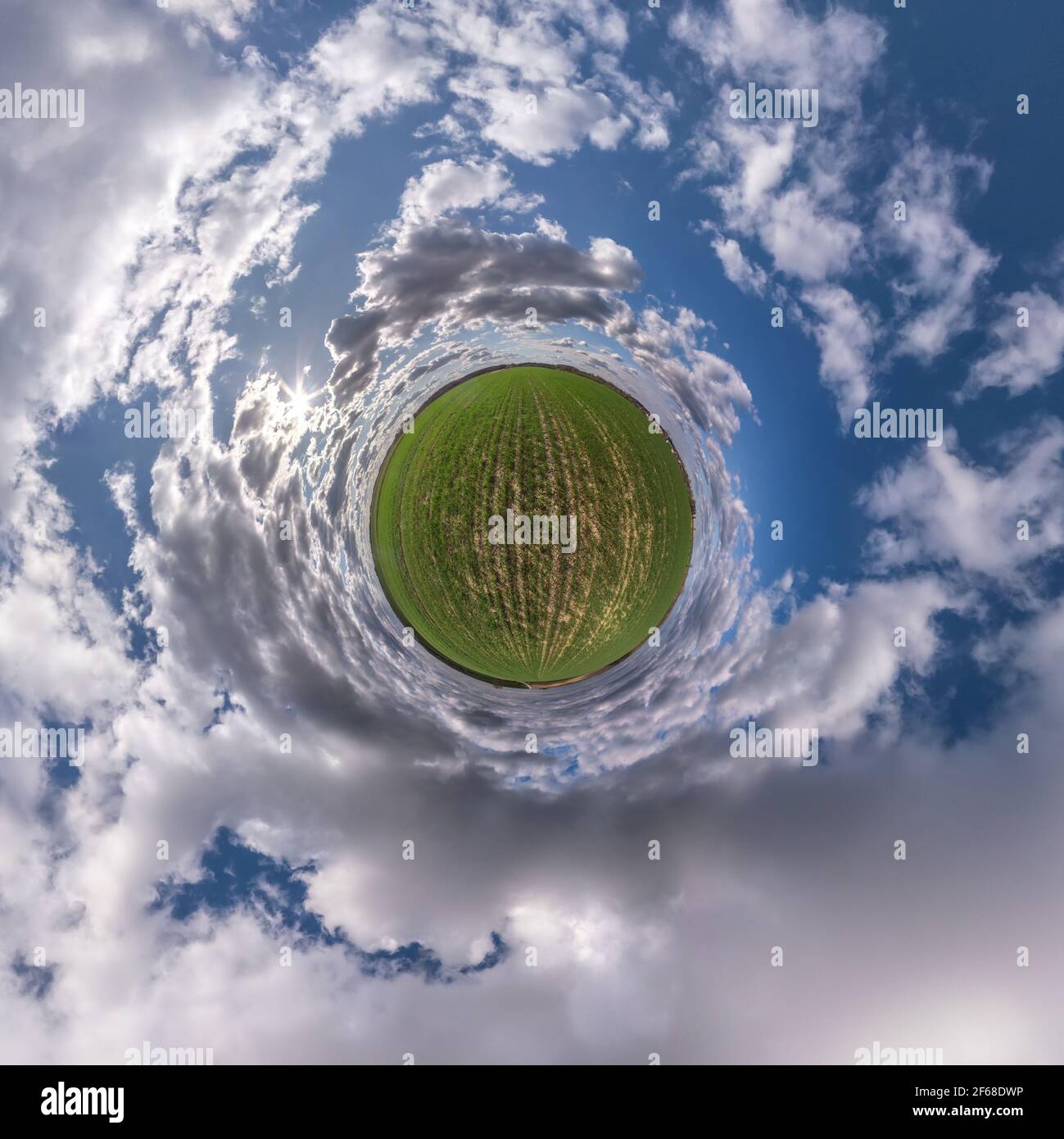 Winziger Planet in blauem Himmel mit Sonne und schönen Wolken. Transformation des sphärischen Panoramas 360 Grad. Sphärische abstrakte Luftaufnahme. Krümmung von Stockfoto