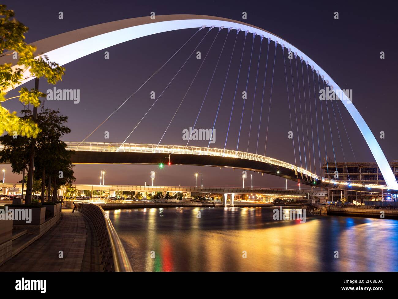 Wunderschöne Aussicht auf die beleuchtete Toleranzbrücke, die nachts von der Dubai Canal Boardwalk, Dubai, VAE, eingefangen wurde. Stockfoto