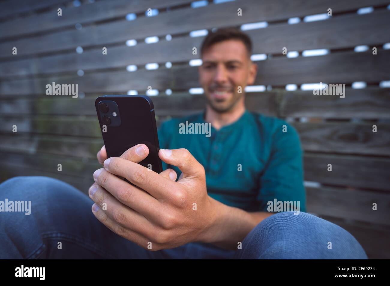 Mann mit einem facetime Videoanruf mit seinem schwarzen modernen Smartphone im Freien. Smartphone betrachten Stockfoto