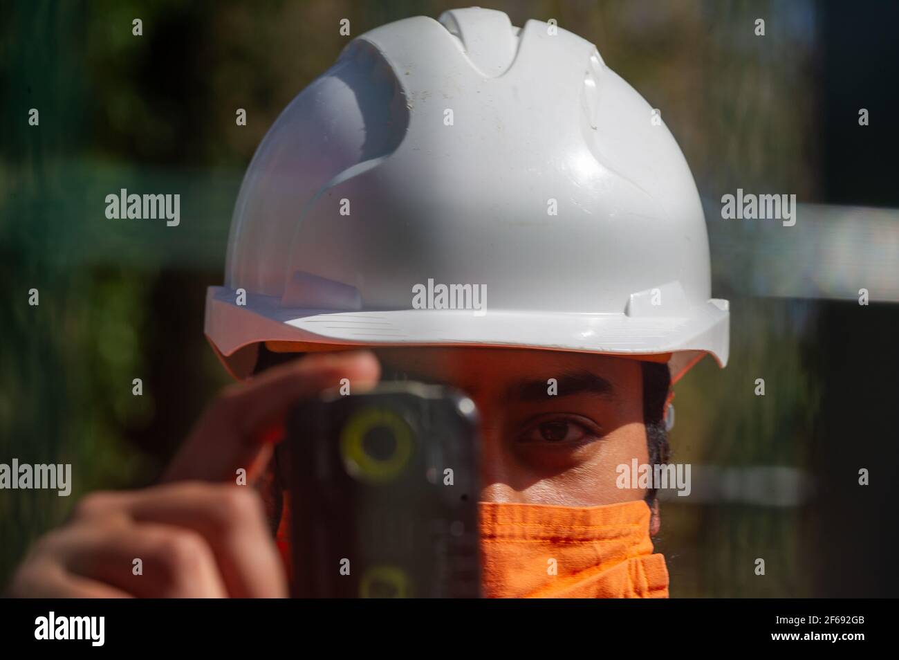 Aylesbury Vale, Buckinghamshire, Großbritannien. März 2021, 30th. Ein HS2 Security Guard filmt erneut ein arbeitend arbeiendes Mitglied der Presse. HS2 haben Road Barn Farm übernommen und Baumfäller waren heute mit großer Freude kettsägende Bäume. Sie benutzten auch einen Baumgreifer, um während der Vogelnistzeit Bäume aus dem Boden zu reißen und angeblich ohne Fledermauslizenz. HS2 haben an der A413 vorübergehend Ampeln aufgesetzt, während sie die Landschaft zerstören und lange Rückschläge verursachen, die Autofahrer lästig machen. Die High Speed 2 Bahnverbindung von London nach Birmingham ist eine riesige Narbenschnitzerei Stockfoto